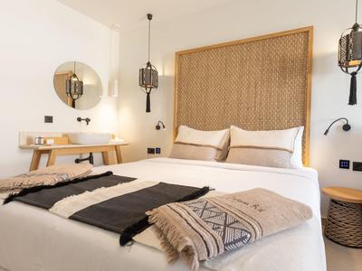 Een moderne hotelkamer met een groot bed, decoratieve kussens en warme houten accenten.