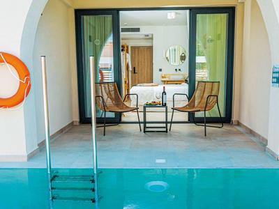 Uitzicht door een boog op een zwembadterras met stoelen en tafel voor een open kamer.