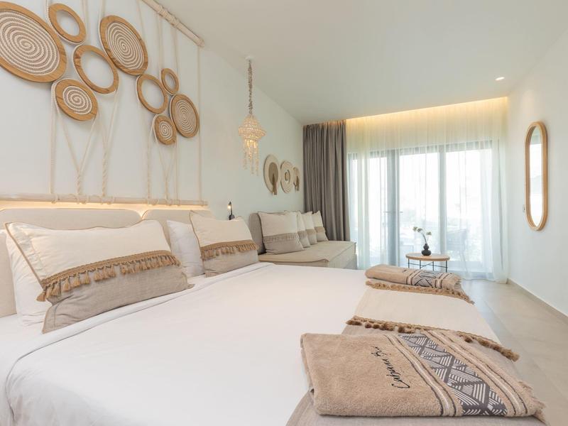 Licht ingerichte slaapkamer met tweepersoonsbed en natuurlijke wanddecoratie.