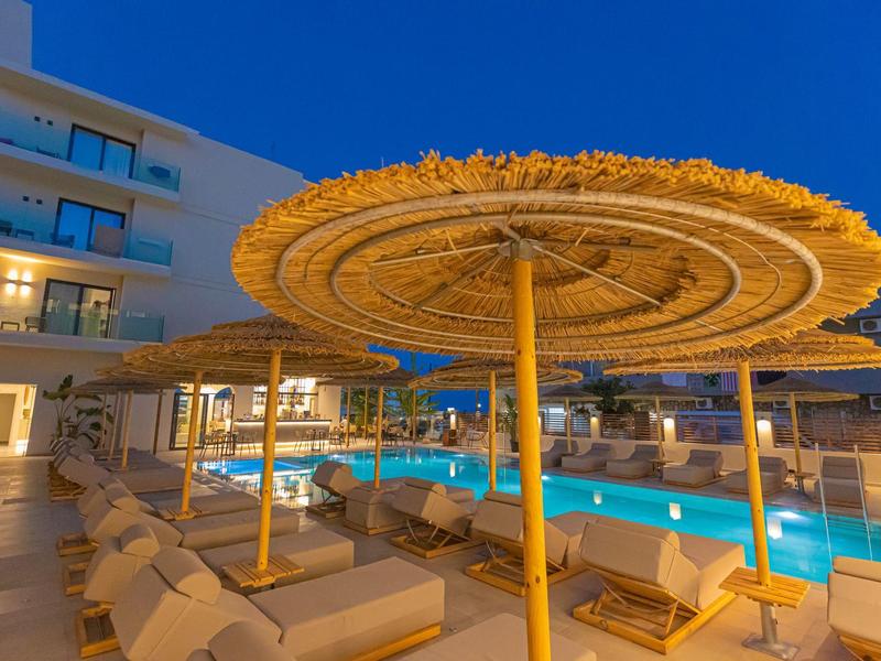 Zwembadgebied van hotel met strooien parasols en ligstoelen bij schemering.