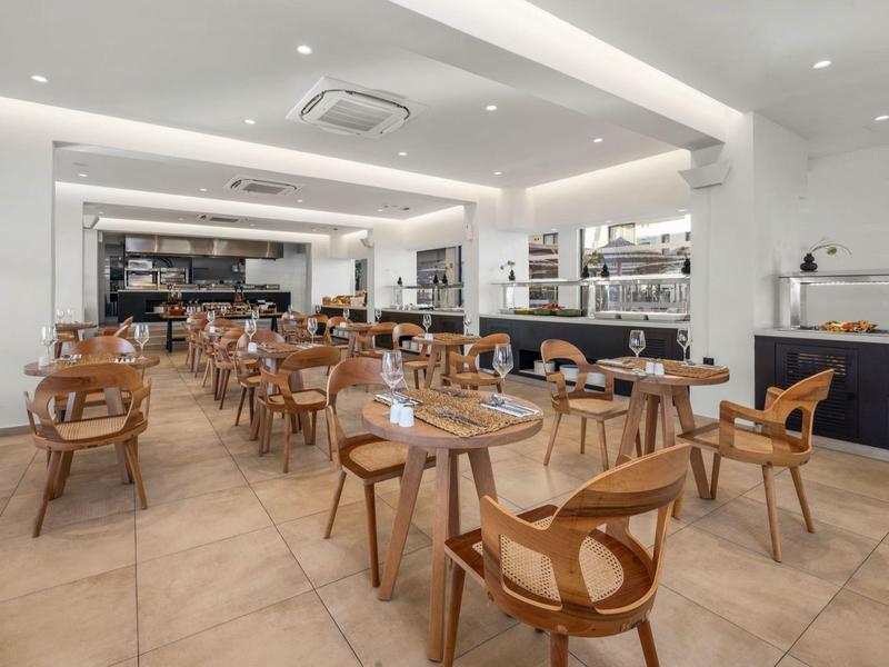 Modern, licht restaurant met bruine stoelen en houten tafels.