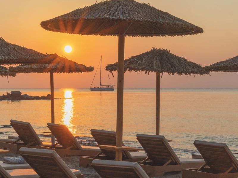 Zonsondergang op het strand met ligstoelen en stro parasols
