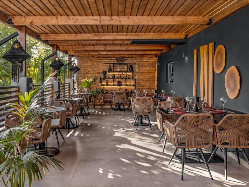 Overdekt terras met tafels, stoelen en planten in een gezellig restaurant