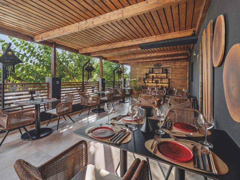 Overdekt buitenterras met eet- en stoelen en stijlvol gedekte plaatsen in een restaurant.