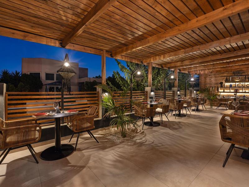 Gezellig overdekt buitenterras van een restaurant met houten balkenplafond en stijlvolle zitplaatsen.