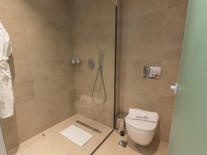 Moderne badkamer met inloopdouche, wandtoilet en beige tegelvloer.