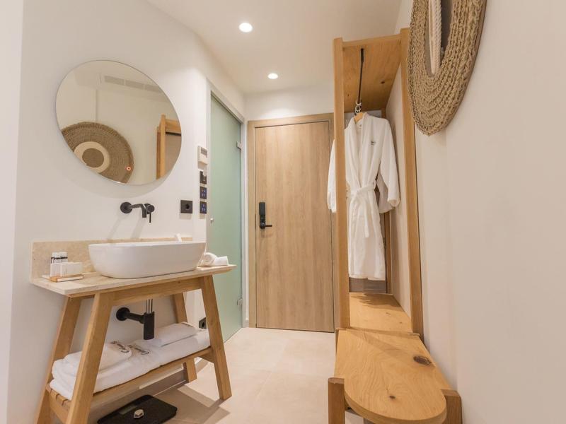 Moderne hotelgang met houten kapstok, spiegel en wasbak.