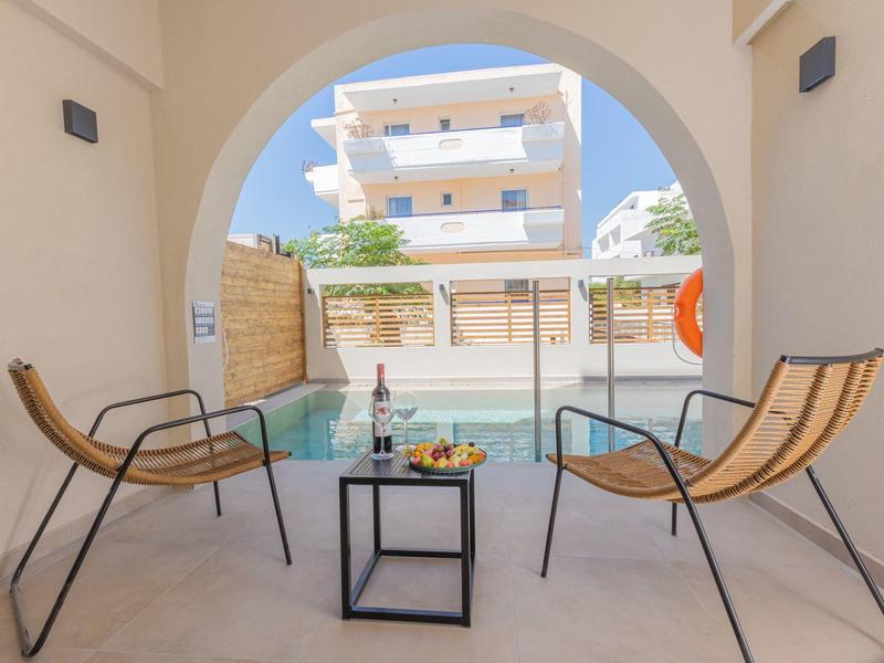 Twee stoelen en een tafel op een terras met uitzicht op een zwembad en een gebouw.