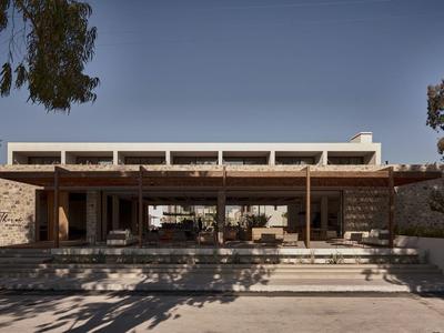 Modernes Gebäude mit Flachdach, breiten Stufen und großen Glasfenstern, umgeben von Bäumen.