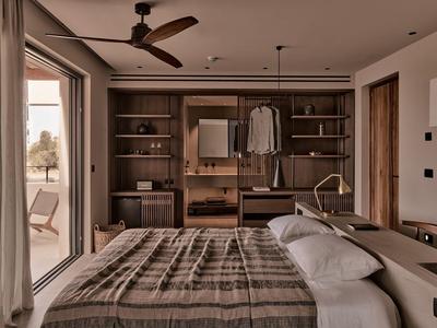 Schlafzimmer mit großem Bett, Holz-Regalen, Schrank, Deckenventilator und Zugang zum Balkon.