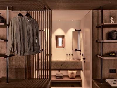 Modernes, minimalistisches Schlafzimmer mit warmem Holz, Regalen, Kleiderstange und indirekter Beleuchtung.