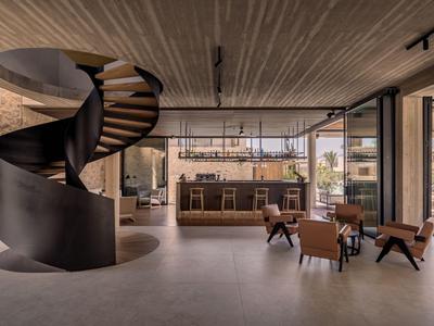 Modernes Hotelinterieur mit Wendeltreppe, Bartresen und Sitzbereich mit Stühlen und Tischen.