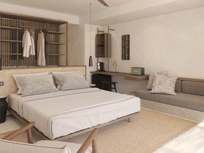 Hell eingerichtetes Schlafzimmer mit Doppelbett, Sofa, Schreibtisch und großem Fenster.