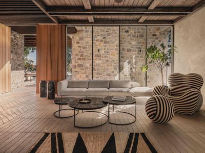 Modernes Wohnzimmer mit Sofa, stilvollen Sesseln und großem Fenster mit Blick auf Steinwand.