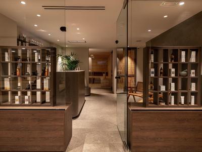 Moderner Eingangsbereich mit dunklen Holzmöbeln, Glaswänden und warmen Lichtakzenten.