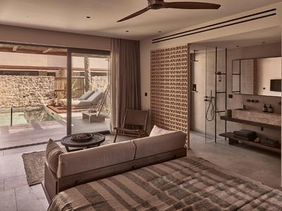 Modernes Schlafzimmer mit Glaswand, angrenzendem Bad und Terrasse mit Pool im warmen Farbton.