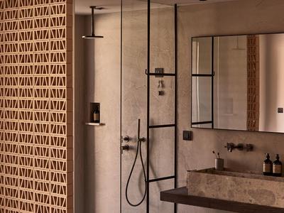 Modernes Badezimmer mit offener Dusche, Sandsteinwaschbecken und Wand aus dekorativen Ziegeln.