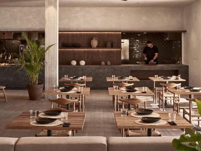 Modernes Restaurant mit Holztischen, schwarzen Tellern und minimalistischer Dekoration.