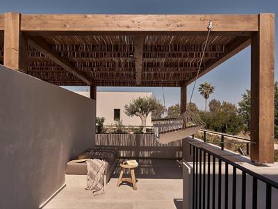 Moderner Außenbereich mit Pergola, Holzmöbeln und Pflanzen in warmem Licht.