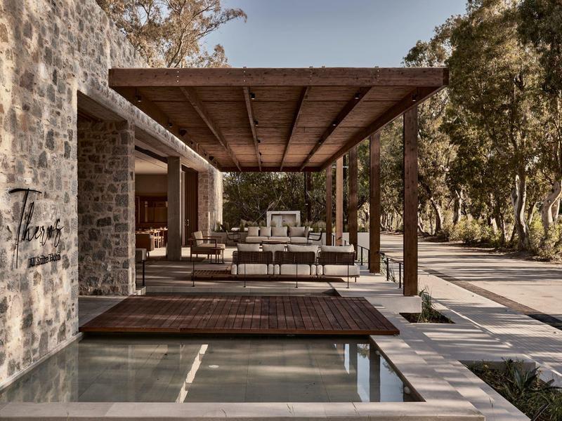 Modernes Haus mit großem, überdachtem Außenbereich aus Holz und Stein neben einem Pool und Garten.