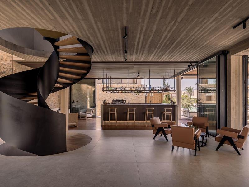 Moderner Innenraum mit schwarzer Wendeltreppe, Holzdecke, Sitzbereich und großer Fensterfront.