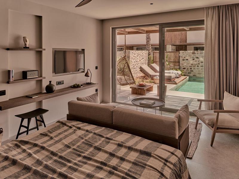 Modernes Schlafzimmer mit Doppelbett, Couch, Flachbildschirm, Holzregalen und Terrasse mit Pool.