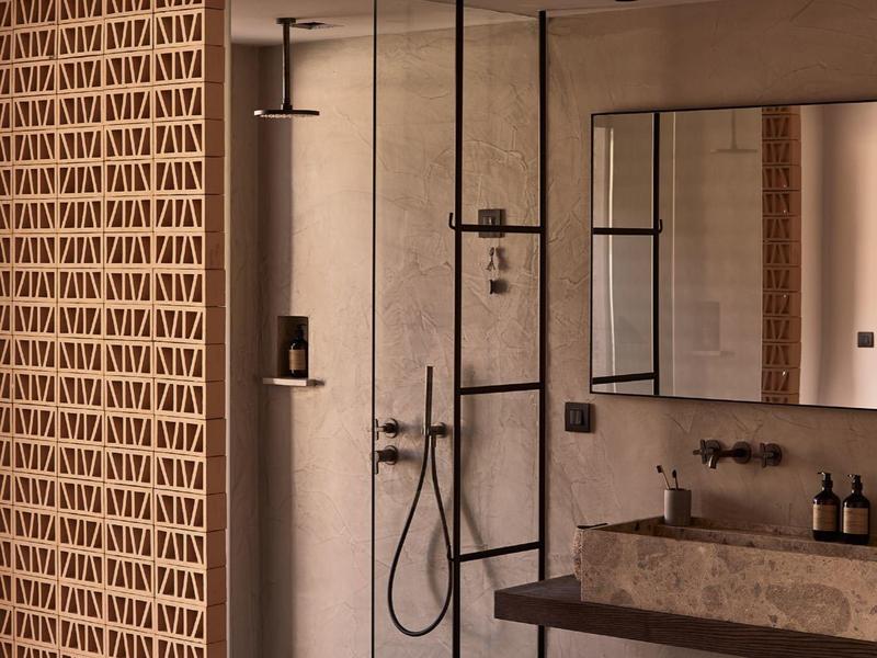 Modernes Badezimmer mit offener Dusche, Sandsteinwaschbecken und Wand aus dekorativen Ziegeln.