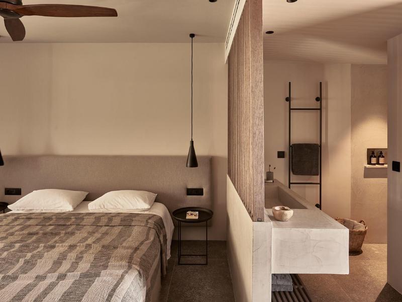 Gemütliches Schlafzimmer mit Doppelbett, dezenten Farben und offenem Zugang zum Badezimmer.