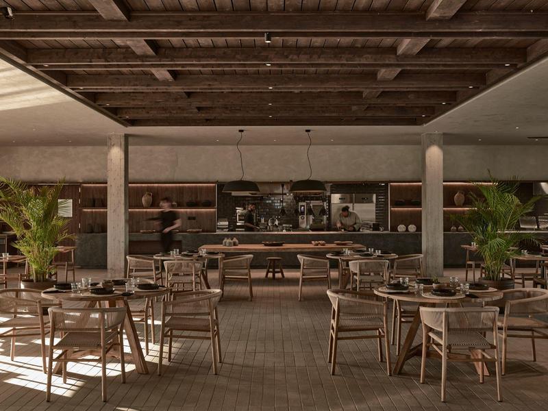 Großes, offenes Restaurant mit Holzmöbeln, vielen Tischen, Pflanzen und dunklem Holzdecke.