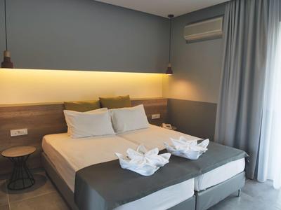 Modern eingerichtetes Hotelzimmer mit Doppelbett, sanfter Beleuchtung und Vorhängen am Fenster.