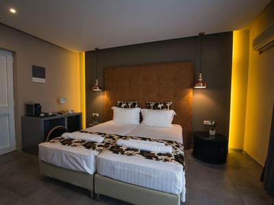 Moderní hotelový pokoj s velkou postelí, nočními stolky a teplým osvětlením.