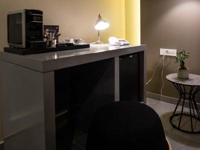 Moderní pracovní prostor v hotelovém pokoji se stolem, židlí a dekorativním osvětlením.