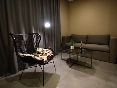 Pohodlný kout s křeslem, pohovkou a stolem v teple osvětleném hotelovém salonku.