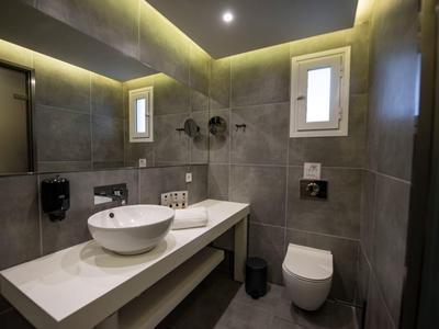 Moderní koupelna s kulatým umyvadlem, toaletou a nepřímým osvětlením.