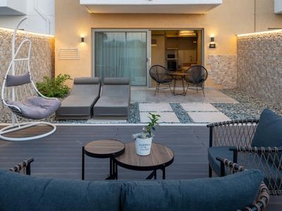 Moderne Terrasse mit Lounge-Möbeln, Hängesessel und Blick auf ein Zimmer mit Küche.