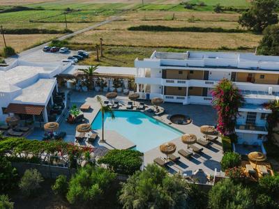 Hotelový areál s bazénem, slunečníky a okolní zelenou krajinou.