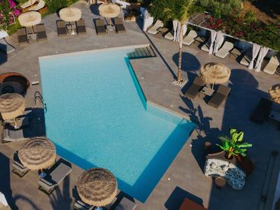 Blick auf einen rechteckigen Außenpool mit Sonnenschirmen und Stühlen in entspannter Atmosphäre.