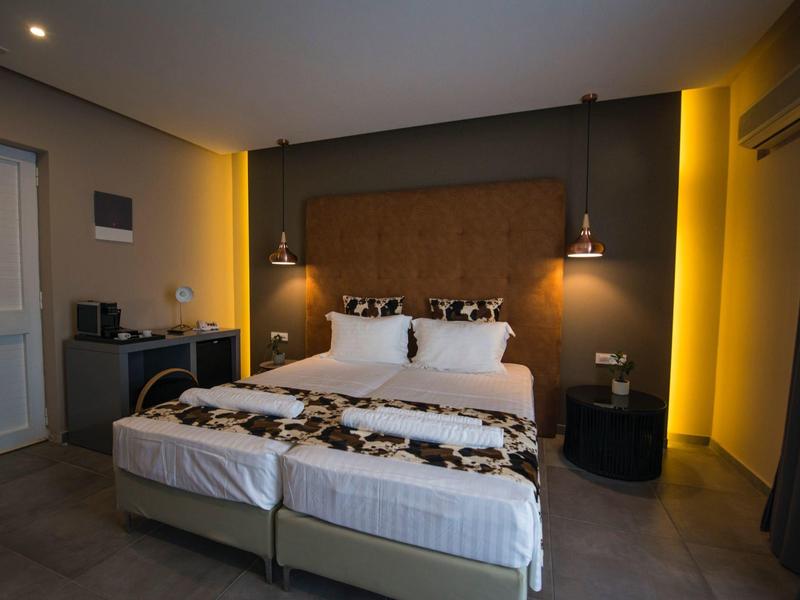 Moderní hotelový pokoj s velkou postelí, nočními stolky a teplým osvětlením.