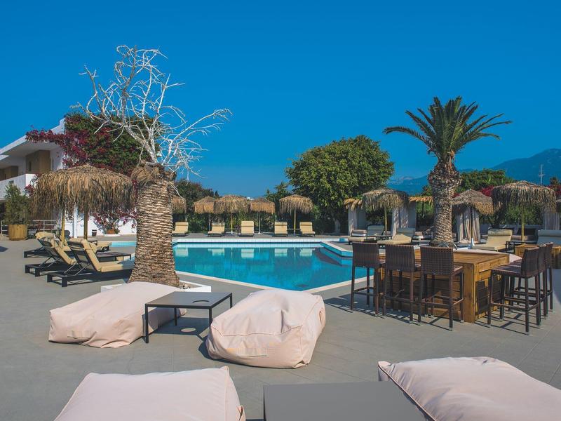 Lehátka a bazén s stoly pod modrou oblohou