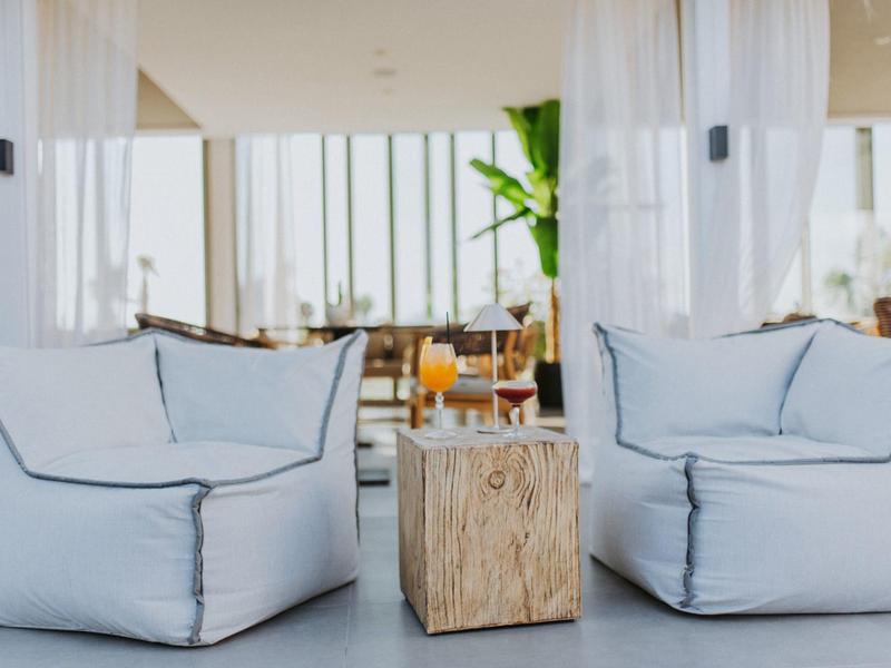 Pohodlný prostor s dvěma bílými křesly a dřevěným stolem v světlé místnosti.