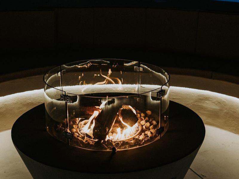 Večerní oheň v moderním ohništi vedle osvětleného bazénu.