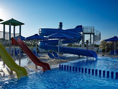 Wasserrutsche mit blauen Spiralen und bunten geraden Rutschen neben einem Schwimmbecken im Freien.