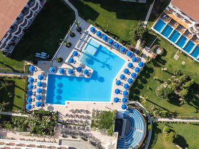 Vogelperspektive eines Schwimmbads mit Sonnenschirmen und Liegestühlen in einem Hotelresort.