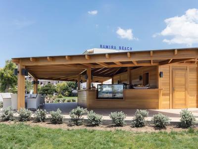 Moderner Holzpavillon mit Schilfdach und Bar in einer grünen Hotelanlage.