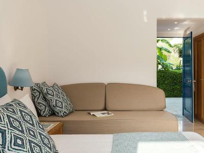 Gemütliche Sitzecke mit beigen Polstern, blauen Kissen und Tür, die zu einem Garten führt.