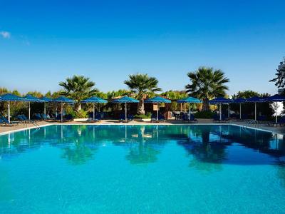 Großer Pool mit klarblauem Wasser, umgeben von Sonnenschirmen und Palmen unter klarem Himmel.