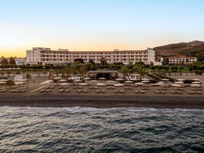 Hotelgebäude mit Pool, Sonnenschirmen und Strand am Meer bei Sonnenaufgang.