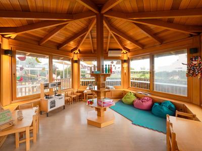 Heller, gemütlicher Holzraum mit bunten Sitzkissen und Spielzeug, ideal für Kinder in einem Hotel.