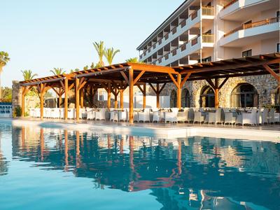 Hotel mit langer Holzterrasse am Pool in warmem Abendlicht.