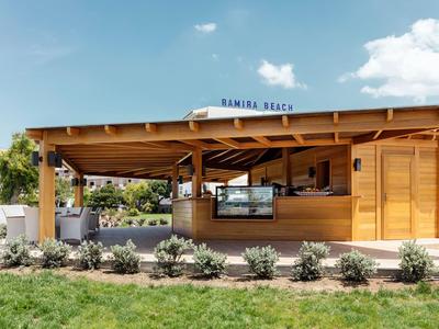 Holzstrandbar mit offenem Servicefenster und grünem Rasen im Vordergrund.